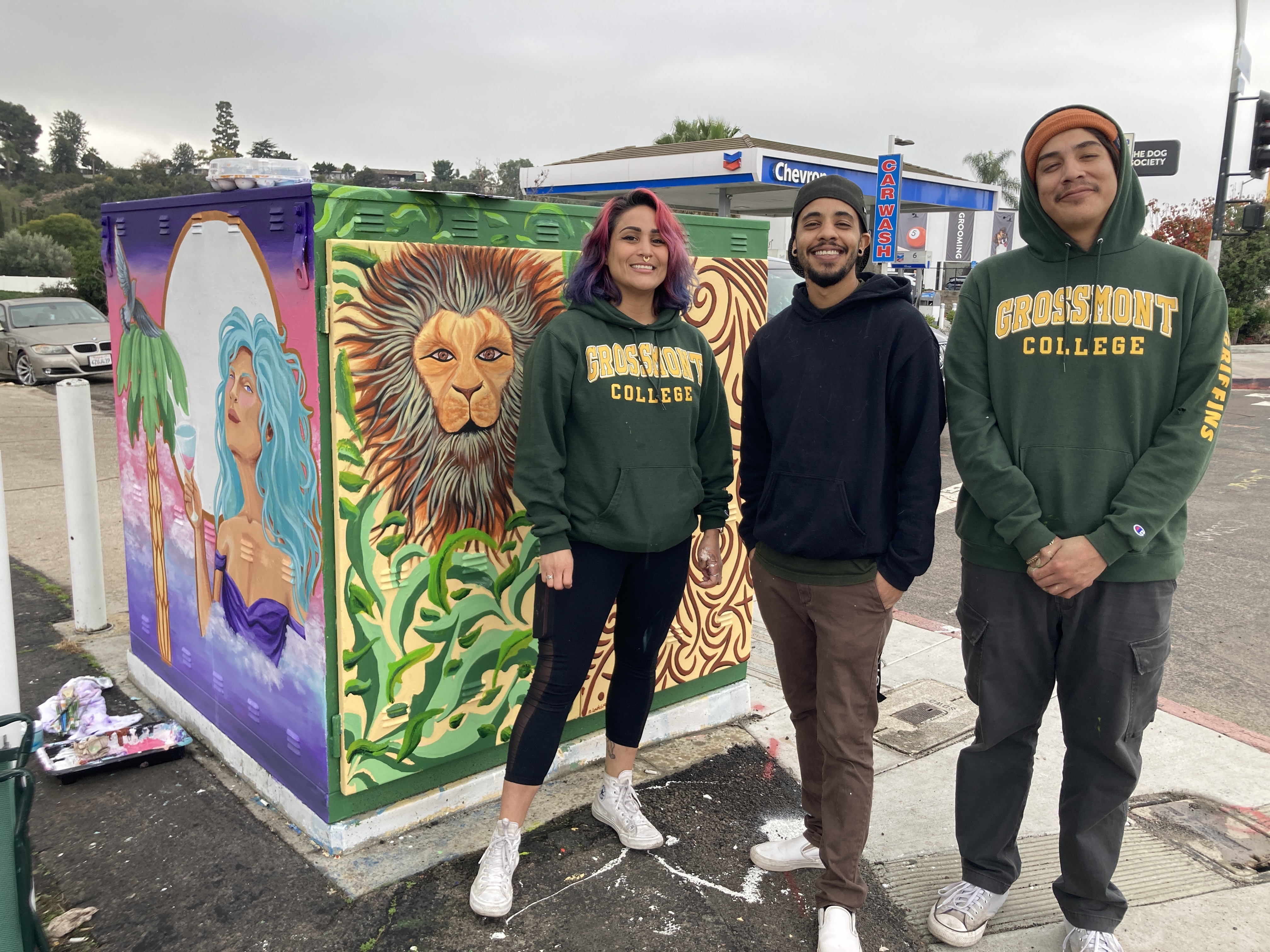 Image of three students in front of mural